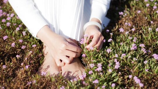 woman with feet in grass picking flowers