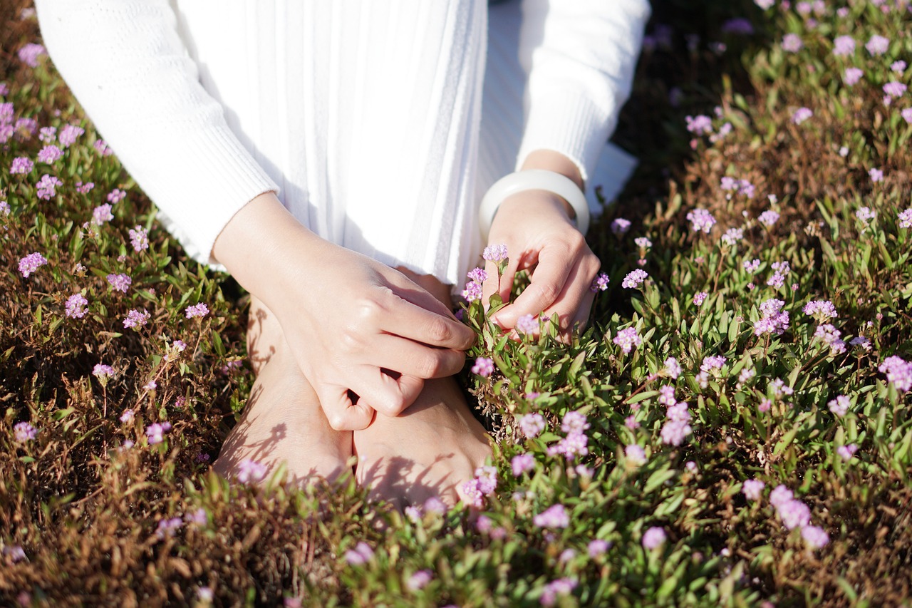 woman with feet in grass picking flowers